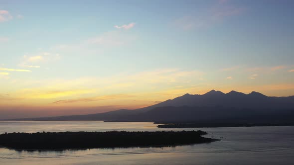 Beautiful pink and orange sunset over an amazing body of water with silhouetted mountains off in the