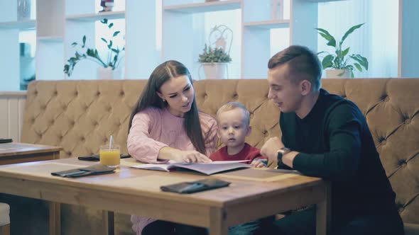 Exciting Family Looks at Menu Sitting on Brown Leather Sofa