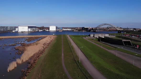 Drone Ascend Over Green Lawn Park With Cars Travelling At Highway With A View Of Bridge Over Noord R