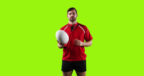 Professional Rugby Player Standing and Throwing a Ball on Green Background