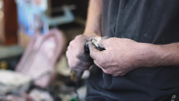 The hands of a caucasian male engraver are looking for a tool on the desktop.