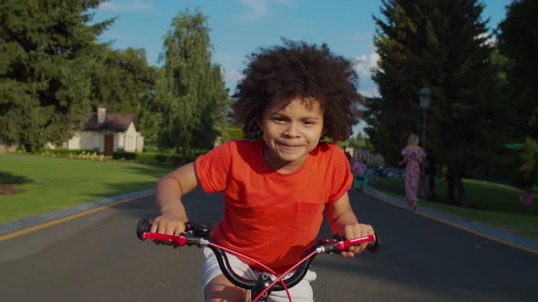 Cute Mixed Race Boy Having Fun Riding Bike in Park