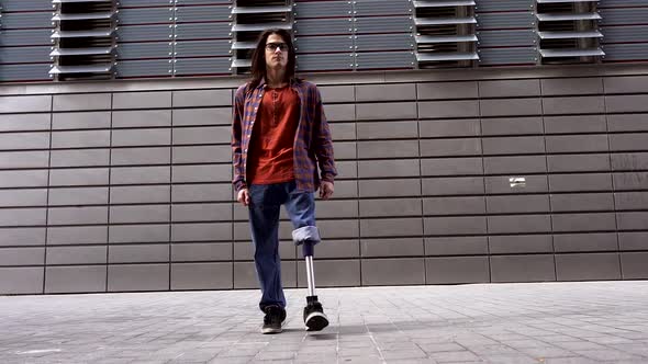 Young man with prosthetic leg walking in front of modern building