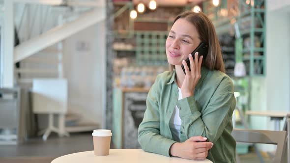 Cheerful Young Woman Talking on Smartphone in Cafe 