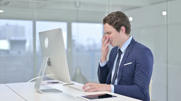 Shocked Young Businessman Reacting To Failure on Desk Top in Office