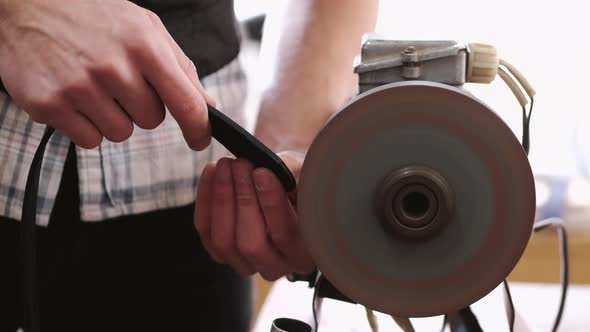 The Craftsman Is Sharpening the Edges of a Belt on a Special Machine