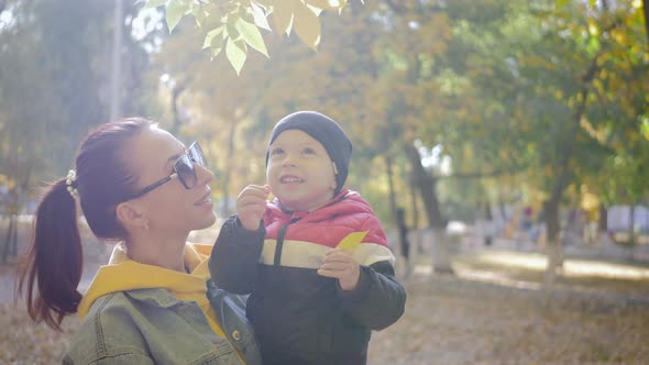 Mom Playing with Son in Autumn Park. Happy Moments Together. Family in the Autumn Park.