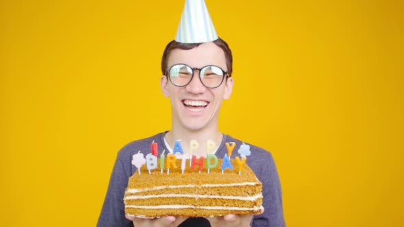 Happy Birthday Concept. Young Funny Man with a Cake o an Orange Background