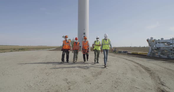 Group of Engineers Walking and Talking on Wind Farm