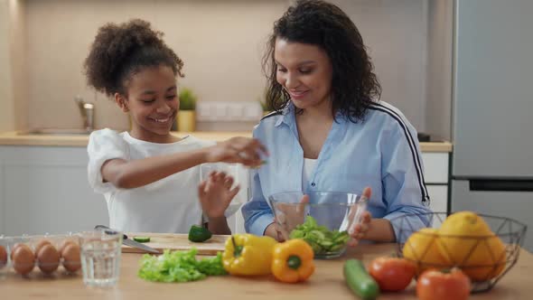 Cheerful Mother and Daughter Prepare Salad in the Kitchen Family Day African Girl Helps Her Mother