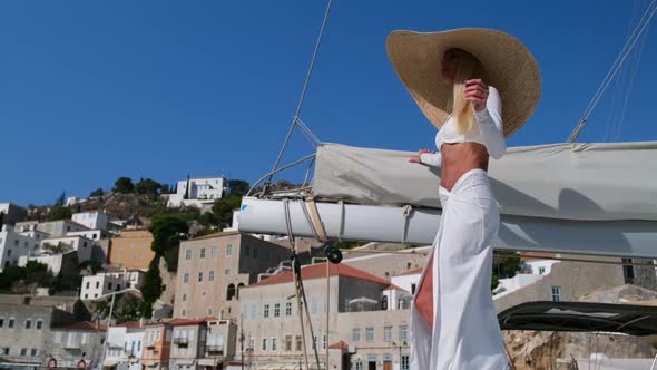 Woman Wearing Straw Hat and White Dress Relaxing on a Cruise Catamaran Sail Boat Hydra Greece