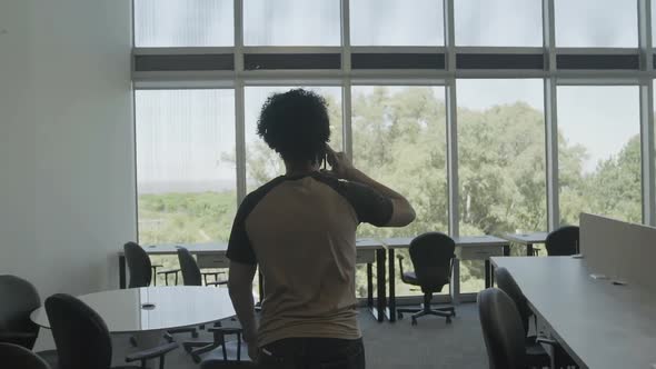 Man walking through office talking on mobile phone