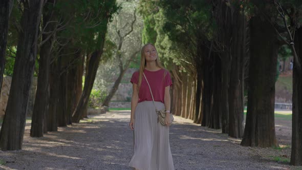 A Young Woman Tourist Walks Along the Valley in the Park Milocer Near the City of Budva