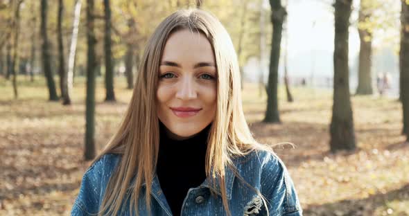 Portrait of Young Attractive Female Who Smiling and Looking at the Camera on Autumn Park, Cheerfully