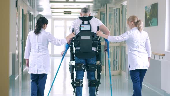 Nurses are Helping a Handicapped Patient to Walk in the Exosuit