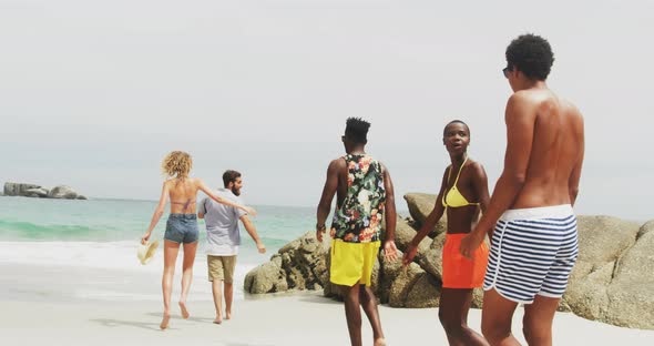 Rear view of mixed-race friends walking on the beach 4k