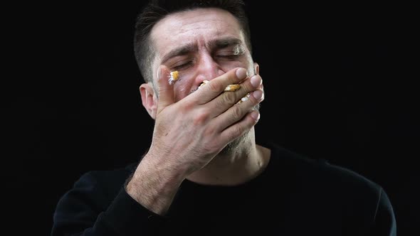 Hungry Male Greedily Eating Cake Against Dark Background, Bulimia Problem