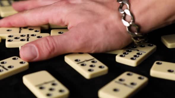 Man hand throws off white dominoes, domino game on black background.