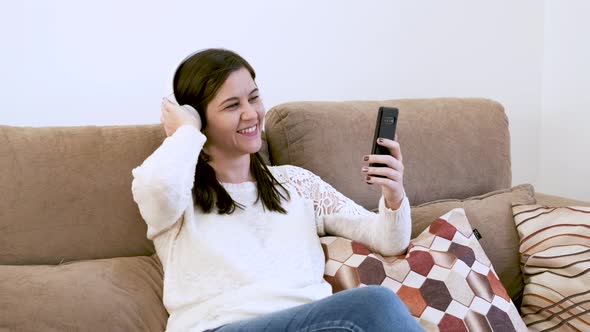 Caucasian young woman listens to music on the wireless headset singing and raising an arm. Concept o