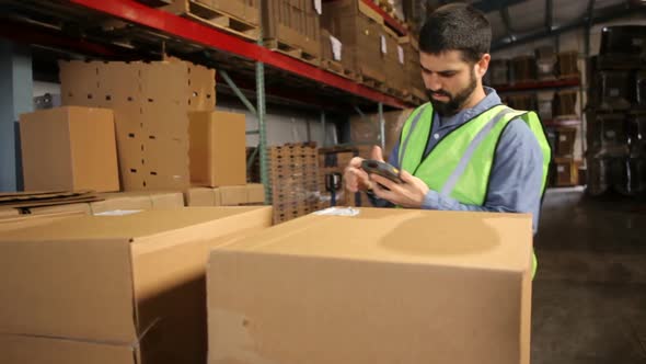 Man in shipping warehouse scans labels on boxes