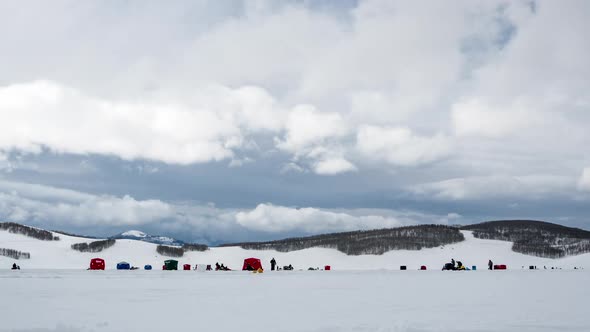 Time lapse of people ice fishing across frozen landscape