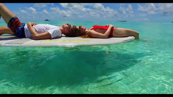 Boy and girl in love on tranquil lagoon beach voyage by blue ocean with white sand background of the