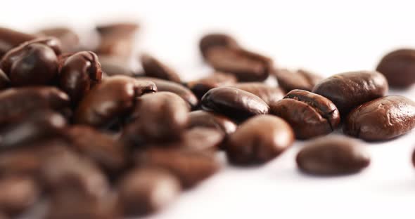 Close Up Shot of Falling Coffee Beans on a White Background Spinning on a Table