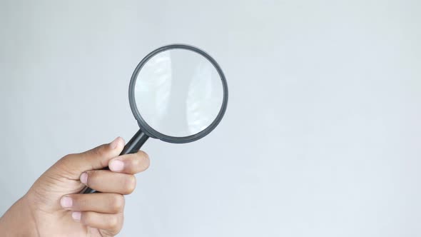Hand Holding Magnifying Glass Against White alt