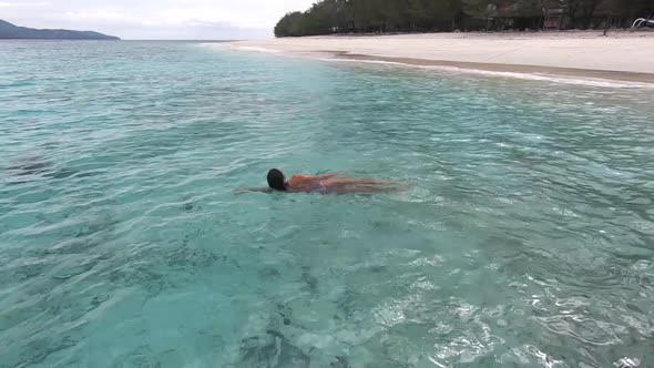 Relaxed Woman Swimming Lying on the Clear Ocean Waves Enjoying the Tranquillity and Tropical Island