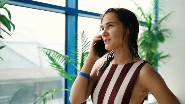 Beautiful Young Woman Relaxing in a Water Park Talking on a Cell Phone While Relaxing at the Weekend