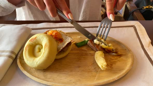 Cutting a soft tuna brioche bun with egg in a restaurant in Tarifa Spain, eating a fish dish for lun