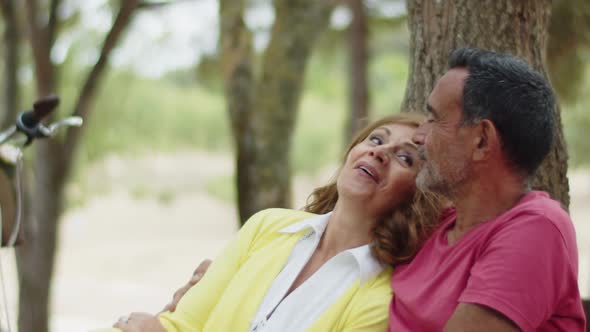 Medium Shot of Cuddling Senior Couple Sitting on Bench in Park