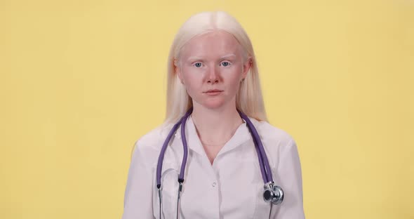 Young Albino Woman in White Coat Puts on a Protective Mask and Looks at the Camera, Portrait