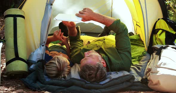 Father and daughter using digital tablet outside tent