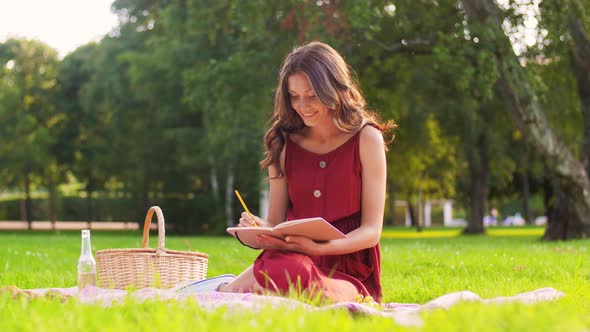 Happy Woman with Diary and Picnic Basket at Park