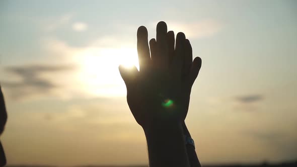 Silhouette of Male and Female Hands Holding Each Other at Sunset Background