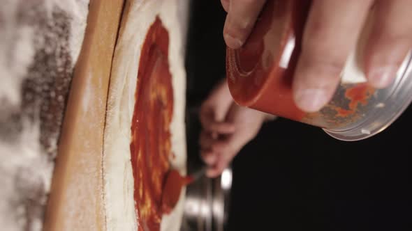 Slow Motion Of Ready-made Pizza Sauce Being Spread On Pizza Dough Before Baking. close up, vertical