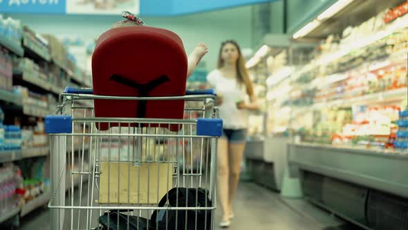 Child Sits in a Specially Equipped Chair in the Supermarket