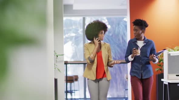 Video of diverse businesswomen walking with smartphone and coffee and talking