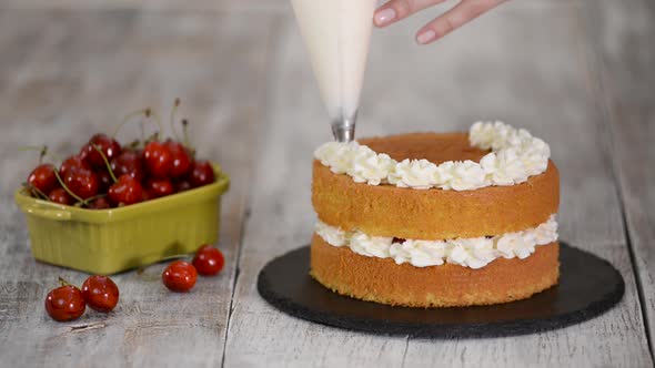 Decorating a Cherry Cake with Cream From the Pastry Bag.