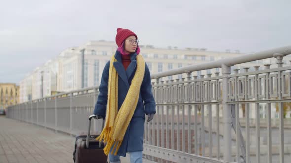 Female Tourist Walking with Luggage on City Bridge