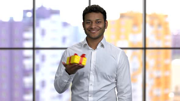 Young Cheerful Brownskinned Man Holds Gift Box in His Right Hand