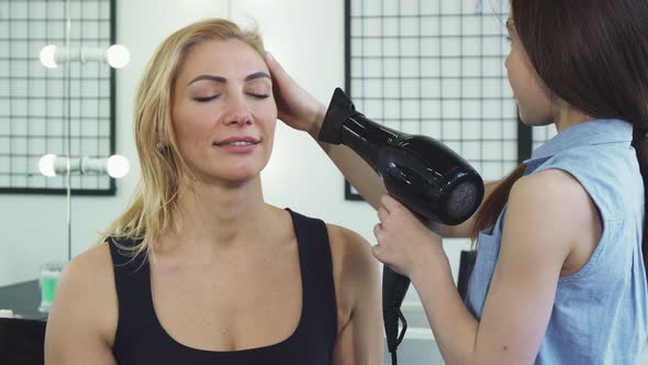 Gorgeous Woman Smiling While Her Daughter Blow Drying Her Hair