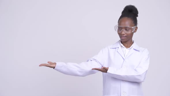 Young Happy African Woman Doctor with Protective Glasses Showing Something