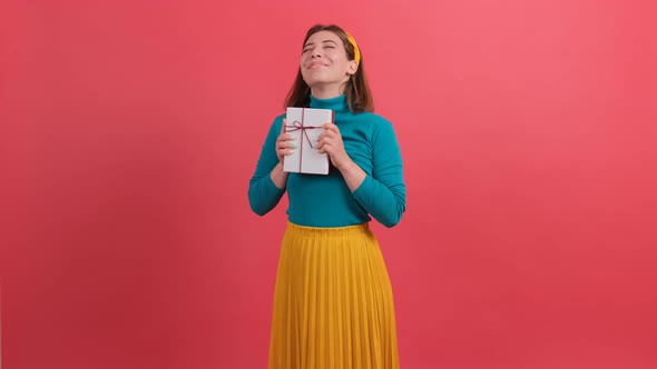 Joyful Woman Embracing Wrapped Gift Box and Smiling with Excitement, Rejoicing