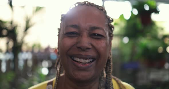 African woman working inside nursery greenhouse while smiling on camera - Green market concept