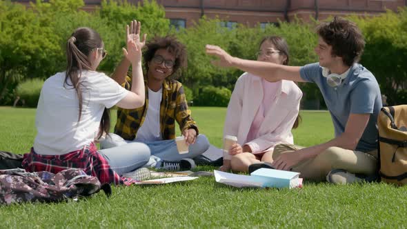 Group of International College Students Sitting on Lawn in Park Giving High Five