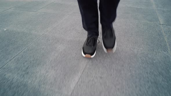 View From Ground Level of Men in Grey Sneakers Walking Along Pavement