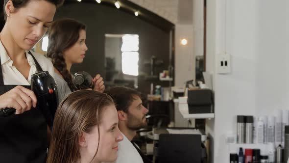 Two hairdresser blow drying their client hair