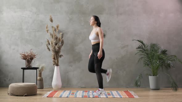 Young Woman Does Sport on the Background of a Gray Concrete Wall